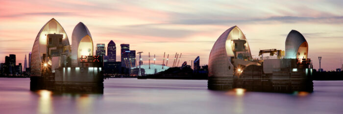 The thames river barrier with Canary wharf in the background at sunset