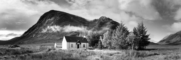 Black and white panorama of a Glencoe white Cottage and Buachaille Etive Mòr Mountain in the Scottish Highlands