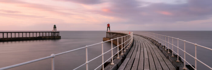 Panorama of Whitby pier lighthouses and harbour at sunset
