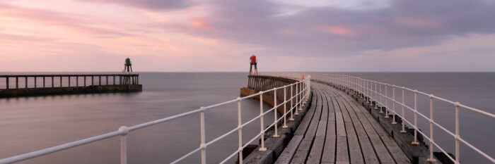 Panorama of Whitby pier lighthouses and harbour at sunset