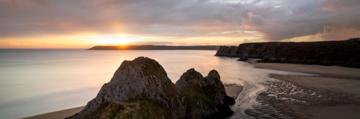 Panorama of the three cliffs bay at sunset in Gower Wales