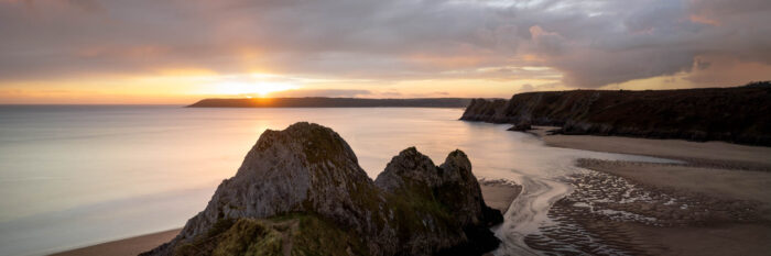 Panorama of the three cliffs bay at sunset in Gower Wales
