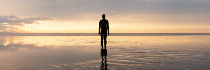 Panorama of Antony Gormley Another place sculptures at sunset on Crosby Beach in Merseyside