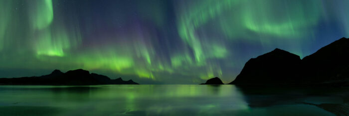 Panorama of Haukland beach with the Aurora Borealis above in the arctic circle