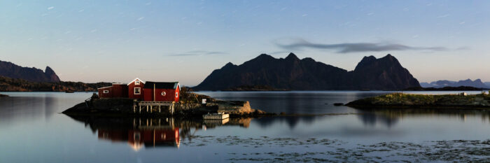 Panorama of a red Rorbu fishing hut under the moonlight in the Lofoten Islands