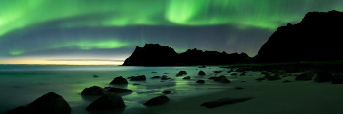 Panorama of Uttakleiv beach at night with the northern lights above in the Lofoten Islands
