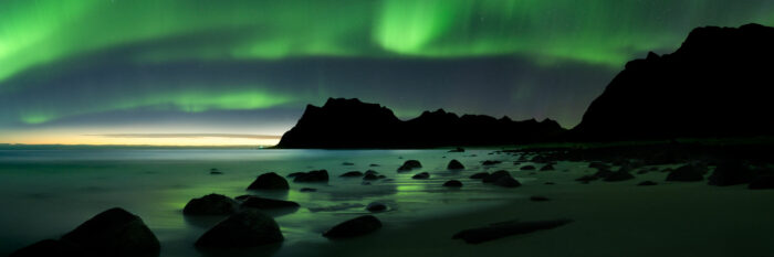 Panorama of Uttakleiv beach at night with the northern lights above in the Lofoten Islands