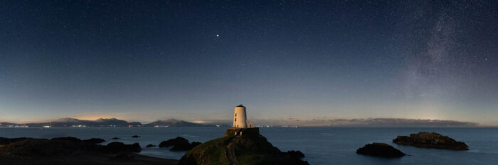 Panorama of a Anglesey Lighthouse under the stars and Milky Way at night in Wales