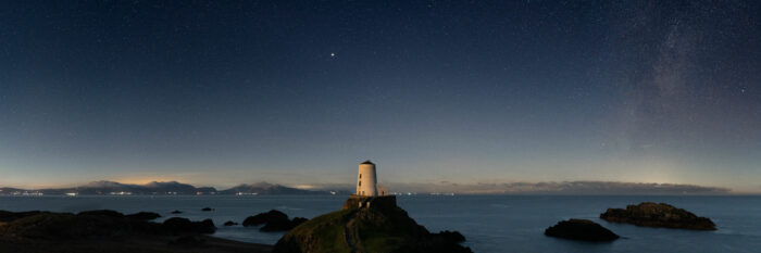 Panorama of a Anglesey Lighthouse under the stars and Milky Way at night in Wales