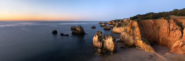 Panorama of the cliffs of the Algarve glowing as the sun rises in Portugal
