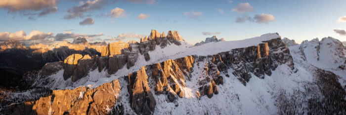 Aerial panorama of the Lastoni di Formin steap west face Dolomia sprouting from the meadows at sunset in the Dolomites, Italy