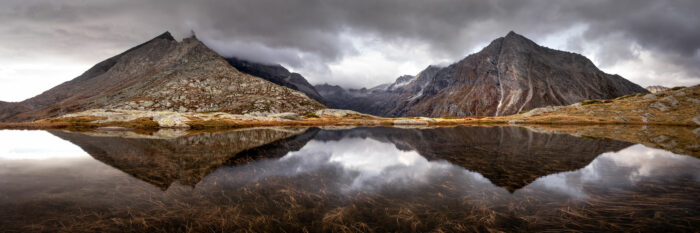 Panorama of Mont Cnies Massif mountains reflecting in a Lake on a stormy Autumn day in the French Alps