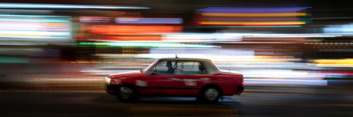 Panoramic art of a Hong Kong Taxi speeding through the neon streets at night