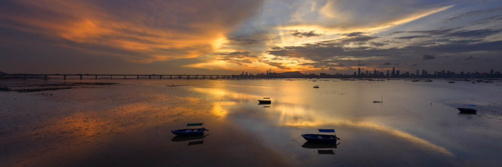 Aerial Panorama of the sunset reflecting in the water at the Lau Fan Shan shoreline in the New Territories, Hong Kong with Shenzhen behind.