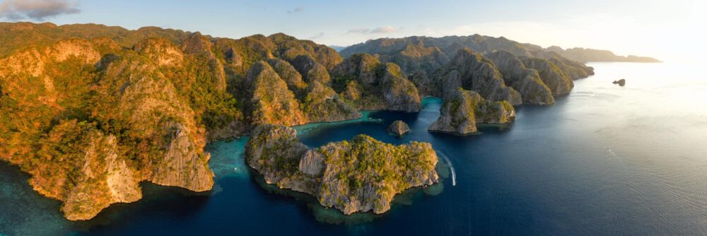 Aerial panorama of the dramatic coast of Coron Island during golden hour in Palawan, Philippines