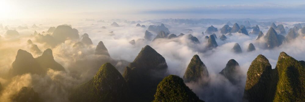 Aerial panorama of a sea of clouds beneath the Karst green peaks of Yangshuo in Guilin, China
