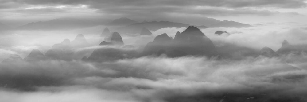 Black and white aerial panorama of Yangshuo mountain peaks above the clouds in Guilin, China